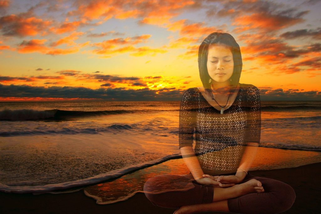 Woman meditating at beach sunset